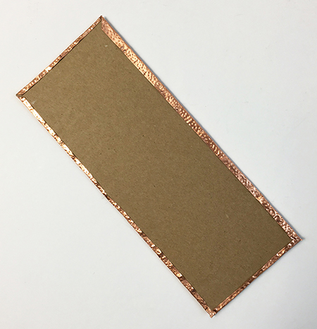 Metal embossing attached to chipboard
