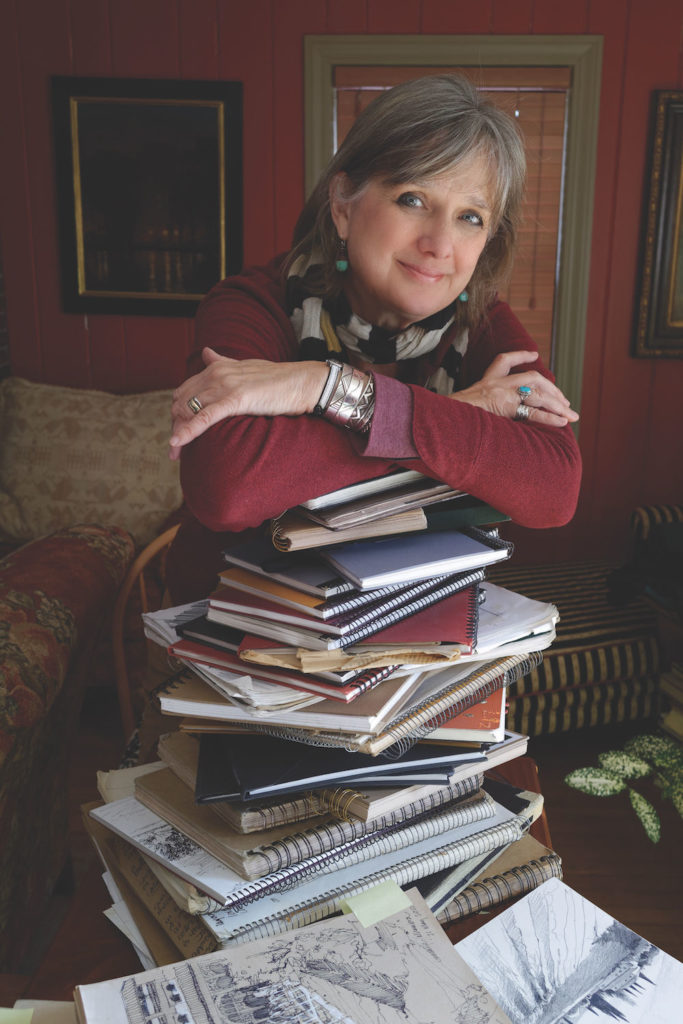Photo of Liz Haywood-Sullivan with a pile of sketchbooks, courtesy of Michael Sullivan | Why Having an Artist Sketchbook is Key to Better Art | Artists Network