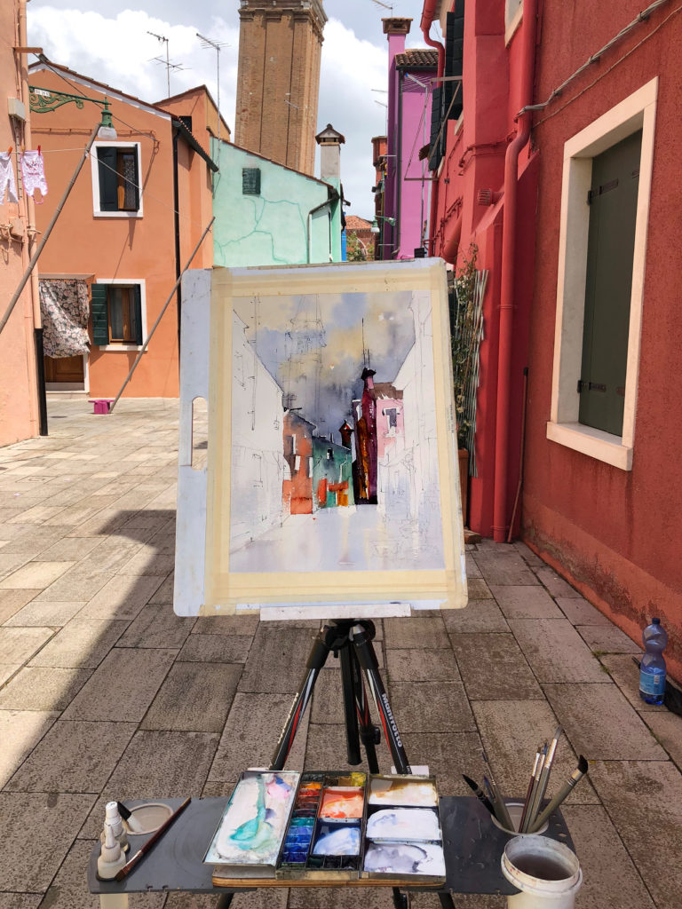 Thomas's easel set up in a colorful street on the Italian island of Burano.